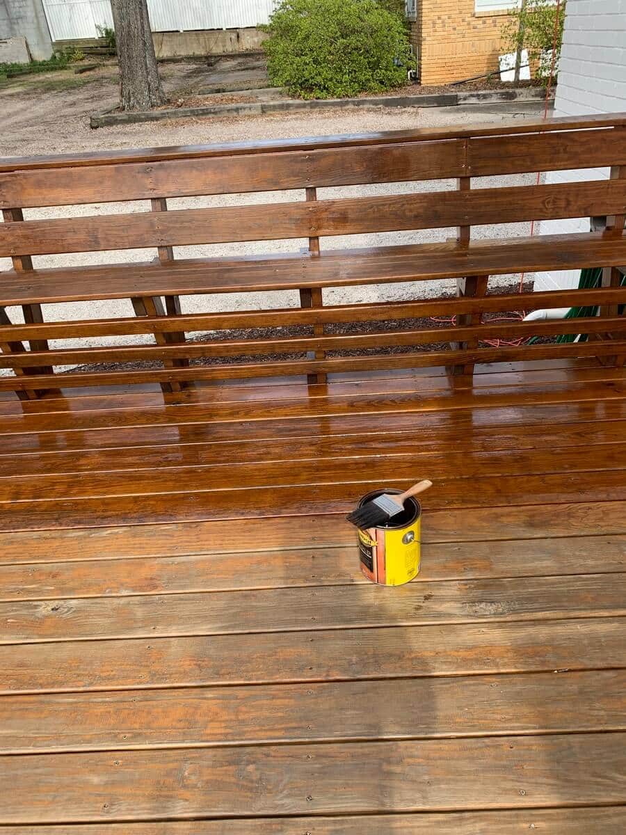 A paint and a paint brush on a wooden deck